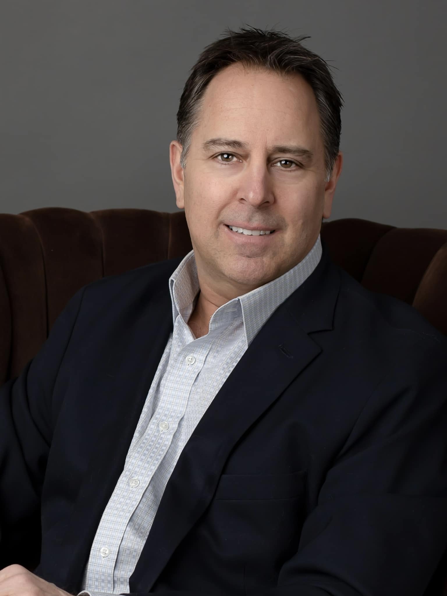 Smiling businessman in blazer seated on chair